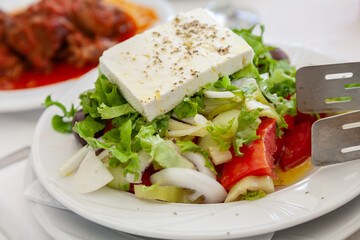 Traditional greek salad with a slice of feta cheese and olives  served in tavern in Halkidiki, Greece. - 748051264