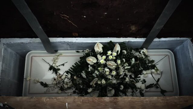 Flowers on the coffin lid are thrown into the grave. Funeral. 