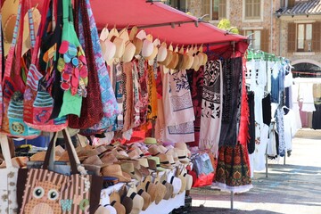 The market stall is adorned with earthy-toned hats and bags, each crafted in traditional style. The...