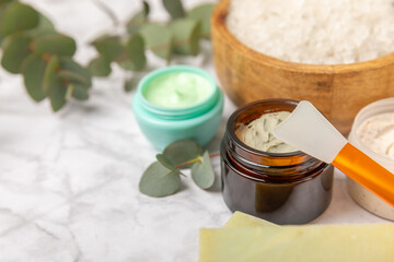 Obraz na płótnie Canvas Beautiful spa composition on a wooden background with eucalyptus leaves. Beauty and fashion spa concept with body cream, scrub, mask, essential oil and sea salt.Cosmetic product. Copy space.