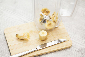 Banana shake in blender. Banana slices inside kitchen blender. Banana smoothie recipe background. Homemade summer breakfast. Fruit cocktail preparation. Top view inside.