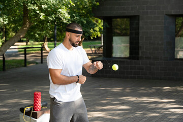 Boxer fighter trains with a boxing fight ball in the park for improved reflexes and coordination