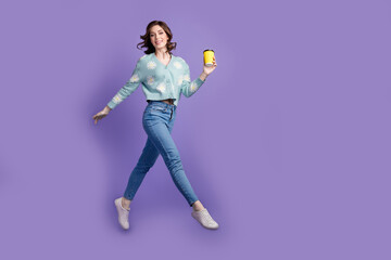 Fototapeta na wymiar Full length photo of cute excited lady dressed flower print cardigan drinking coffee jumping high empty space isolated violet color background