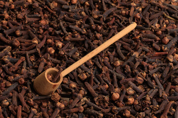 A pipe shaped wooden spoon on a clove pile