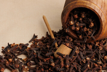 Clove pour out from a wooden cup with a pipe shaped wooden spoon