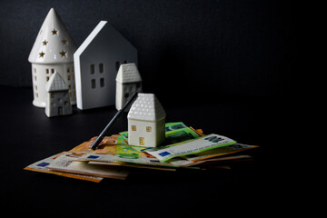 ceramic house with euro money and key on black background. concept, people tied themselves to the...