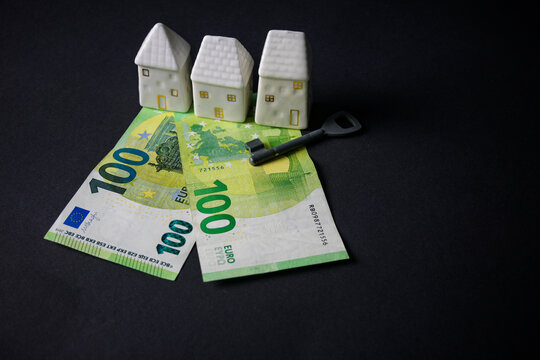 ceramic house with euro money and key on black background. concept, people tied themselves to the bank for a mortgage