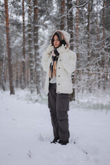 Terapia lasem. Młoda ładna dziewczyna ciepło ubrana spaceruje po lesie zimą. 