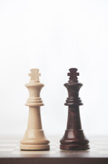 CHESS PIECES OF WHITE KING AND BLACK KING FACING EACH OTHER, ON TOP OF CHESSBOARD
