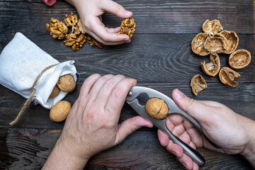Walnuts, a nutcracker on a wooden table. A man cracking nuts.