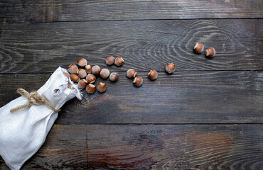 Hazelnuts, a bag and a nutcracker on a wooden table.