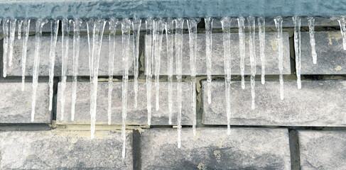 Icicles hang from the brick wall of the building