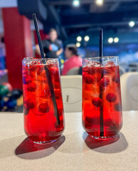 Cherry drink with ice in a glass on a table in a cafe