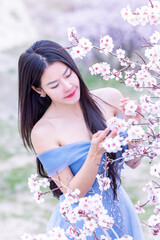 Beautiful woman in blue dress on rocks mountain. Cheerful woman relax outdoor with beautiful sky and pink flowers in holiday vacation. Woman tourist enjoy amazing mountain view. Travel and freedom..