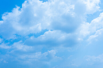 Blue sky adorned with fluffy white clouds on a bright summer day, creating a beautiful and clear...
