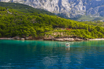 A small boat with tourists slowly floats on clear water. Amazing coastline. Aerial photography. The...