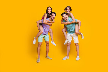 Fototapeta na wymiar Full body photo of positive cheerful guys piggyback girlfriends isolated over vibrant color background