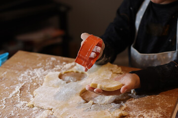child's hands messy making fancy cookie for Easter a lot of cookie cutter on a wood board wearing...