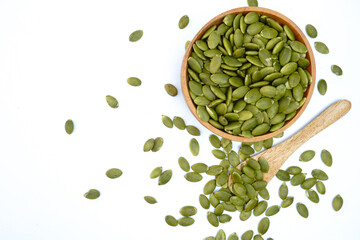Raw peeled pumpkin seeds in a wooden bowl and spoon concept background