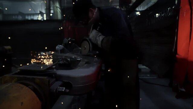 Bright Stream of Golden Sparks Fly to Camera. Welder at Metal Production Factory Works With Grinding Tool, Wheel. Heavy industry. Angle grinding work. Close Up, Cinematic, Slow Motion, Dolly In