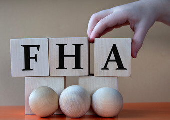 A child's hand places a large cube next to other cubes. FHA acronym concept