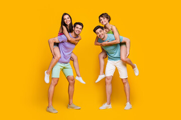Obraz premium Full length photo of people rest relax guys piggyback girls isolated shine color background