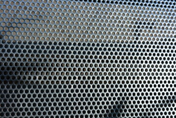 Metal mesh, background, with round identical holes, metal structure with shadow and light.