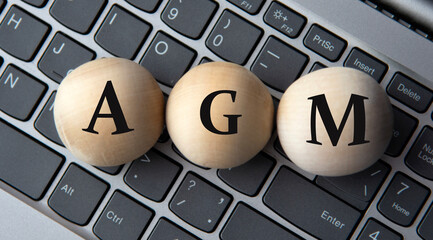 AGM - acronym on wooden balls on laptop keyboard background
