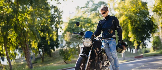 Cercles muraux Moto motorcyclist in outfit with motorcycle in sunglasses and jeans in summer