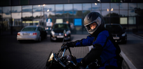 female motorcyclist close-up in a helmet in the evening on a motorcycle in the city.