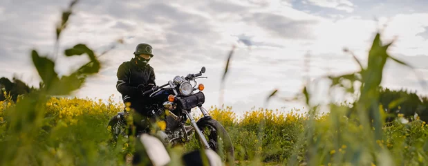 Foto op Plexiglas Motorfiets male motorcyclist on a retro custom motorcycle in a blooming yellow field in summer.