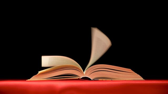 Quickly flipping pages of a thick book on a red black background