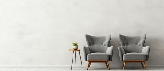 A grey armchair and a wooden chair are placed in front of a stark white wall. The chairs are positioned side by side, creating a simple and minimalist setting. - Powered by Adobe