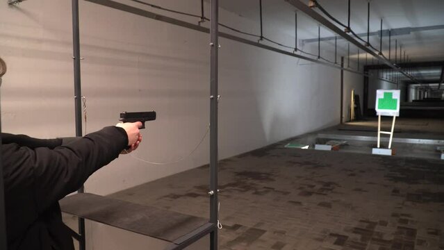 A girl fires a gun. Shooting range. Shooting from a gun. Shooting from a machine gun. Training in shooting. Guns.
