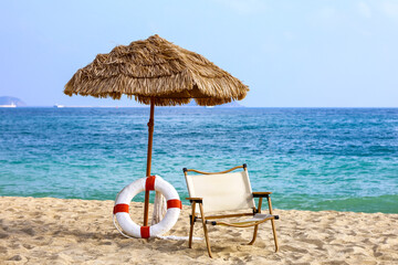 Tropical sandy beach, view to the parasol, life ring and chair on sea resort. Background for vacation and travel