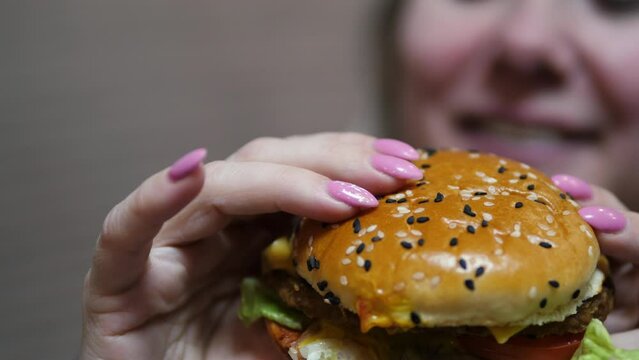Tidbit, Cheeseburger in the arms of a smiling Caucasian woman whose face is out of focus. fast food concert, unhealthy diet