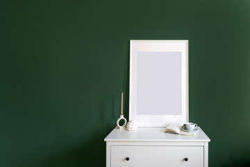 Empty picture in frame on white drawer dresser on green wall background