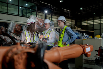 team engineers inspecting on machine with smart tablet. Worker works at heavy machine robot arm. The welding machine with a remote system in an industrial factory. Artificial intelligence concept.