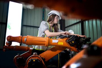 Factory engineers inspecting on machine with smart tablet. Worker works at heavy machine robot arm. The welding machine with a remote system in an industrial factory. Artificial intelligence concept.