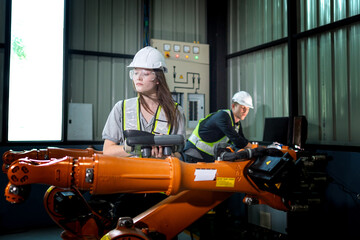 Fototapeta premium Factory engineers inspecting on machine with smart tablet. Worker works at heavy machine robot arm. The welding machine with a remote system in an industrial factory. Artificial intelligence concept.