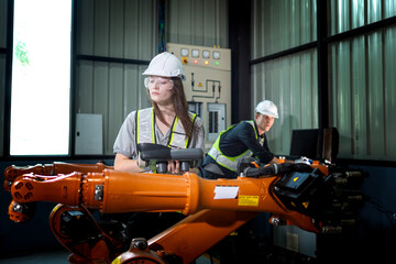 Fototapeta premium Factory engineers inspecting on machine with smart tablet. Worker works at heavy machine robot arm. The welding machine with a remote system in an industrial factory. Artificial intelligence concept.