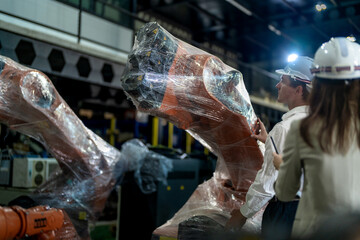 Business engineers meeting and checking new machine robot. Workers walking at warehouse industry welding machine. business negotiation concepts and technology. women Using smart Tablet to present man.