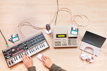 top view of male music producer, composer, arranger hands arranging a hit song on synthesizer keyboard, sequencer, laptop computer. music production or recording concept - 748110666