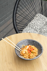 Udon noodles with shrimp and fried vegetables in bowl angle view