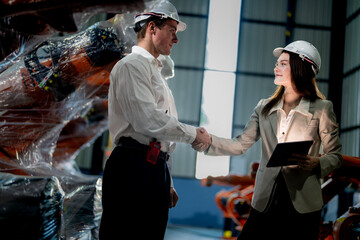 Business engineers meeting and checking new machine robot. Workers walking at warehouse industry welding machine. business negotiation concepts and technology. women Using smart Tablet to present man.