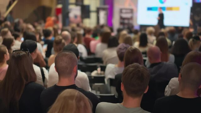 Audience attentively listens to female speaker at entrepreneurship conference. Diverse group of people engaged in start-up seminar. Ideal for topics on youth entrepreneurship, business incubators
