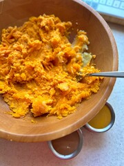 boiled pumpkin and potatoes, crushing pumpkin and potatoes in a wooden bowl, preparing pumpkin puree, spices in containers