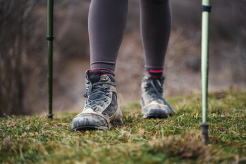 Closeup of low angle view of female legs in hiking shoes walking on a trail, traveler with trekking poles, tourism, sports, active lifestyle concept