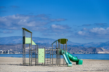 Slider and playground equipment in the sand of San Juan Beach, A