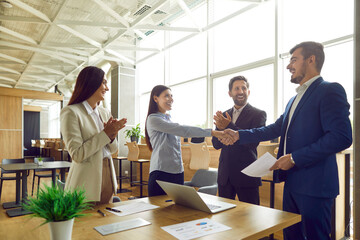 Successful collaboration as a diverse group of business people in the office exchange handshake. This symbolic gesture reflects completion of successful work, partnership and teamwork.